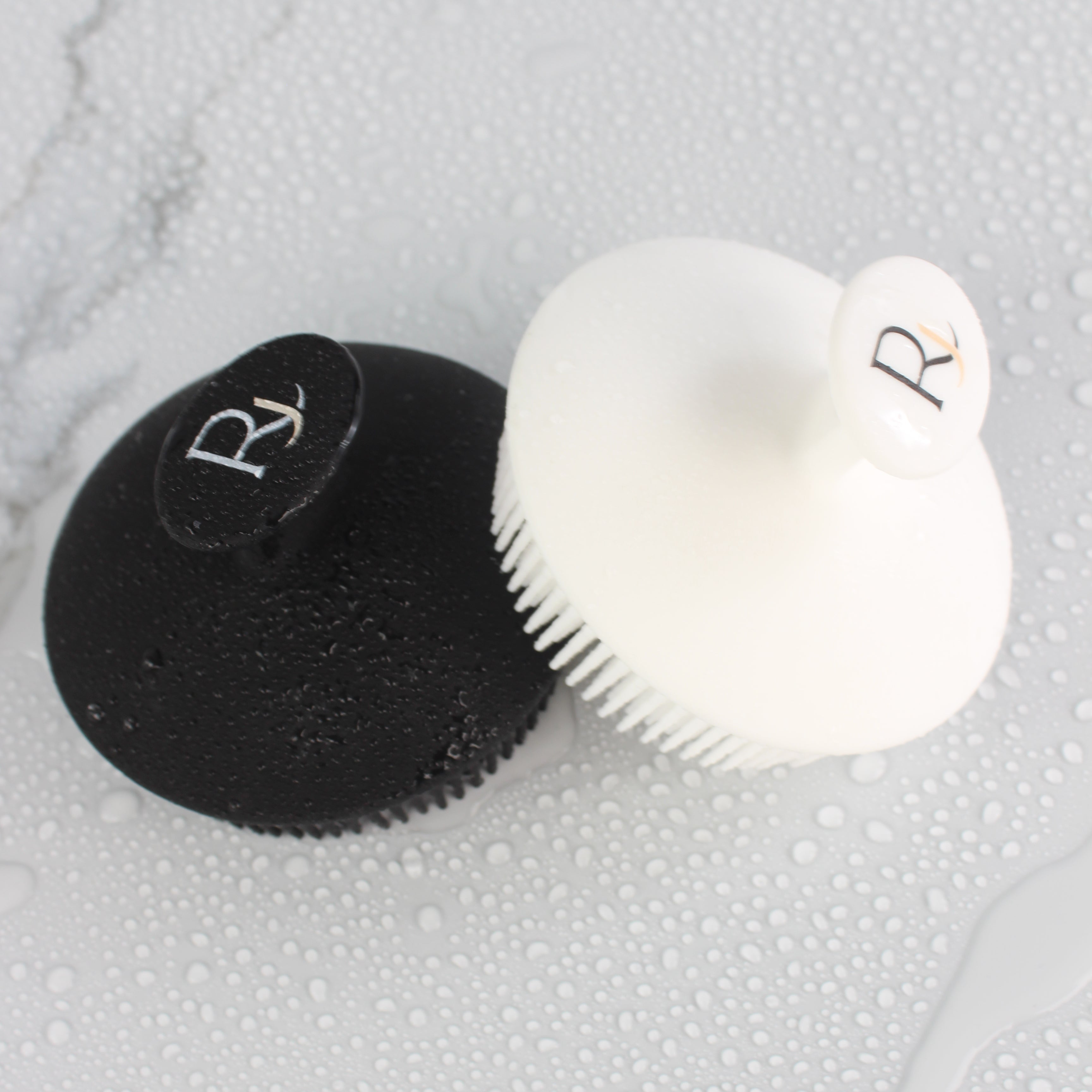 Black and White Raqiia Body Scrubbers on wet white marble