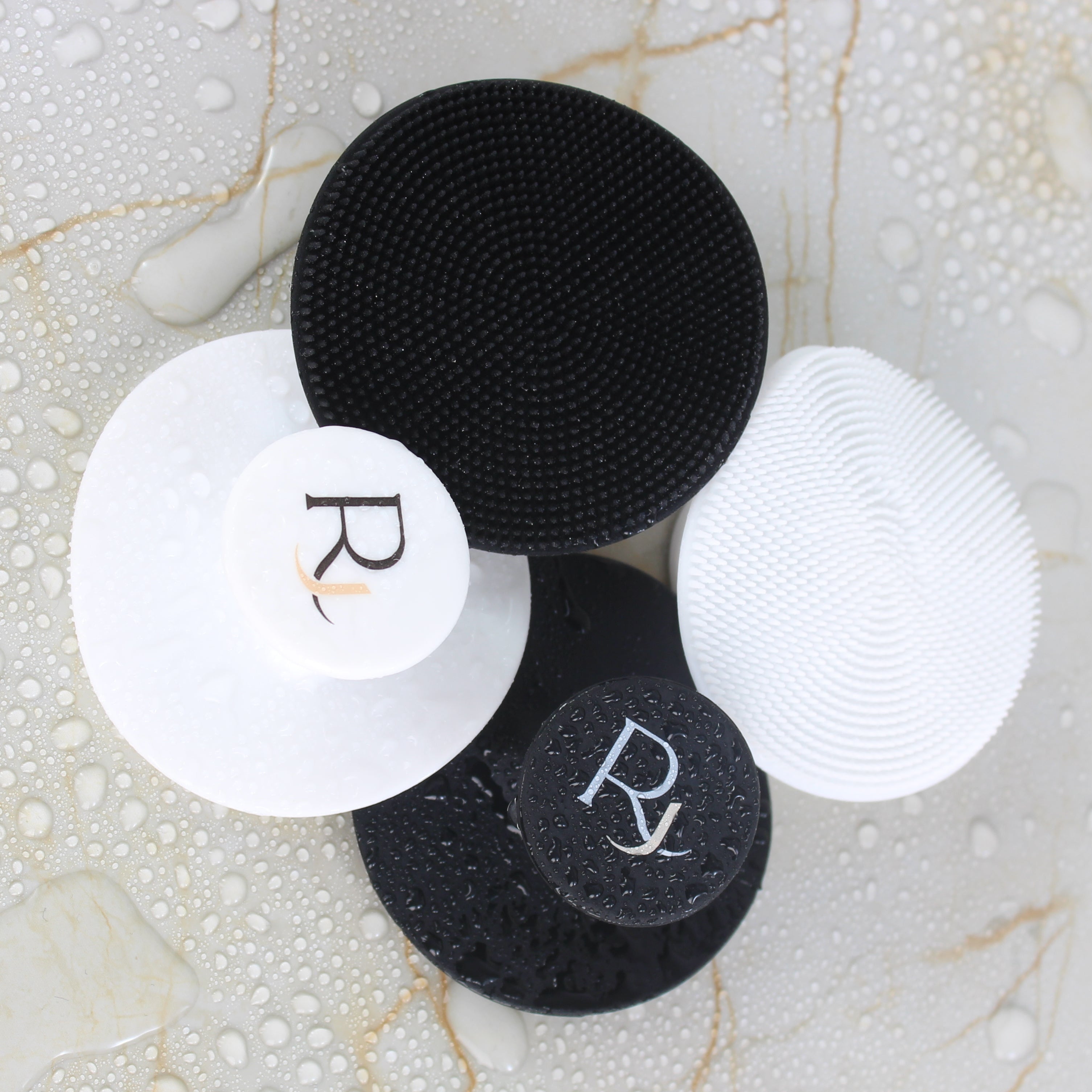 Black and White Raqiia Face Cleansers on wet golden marble