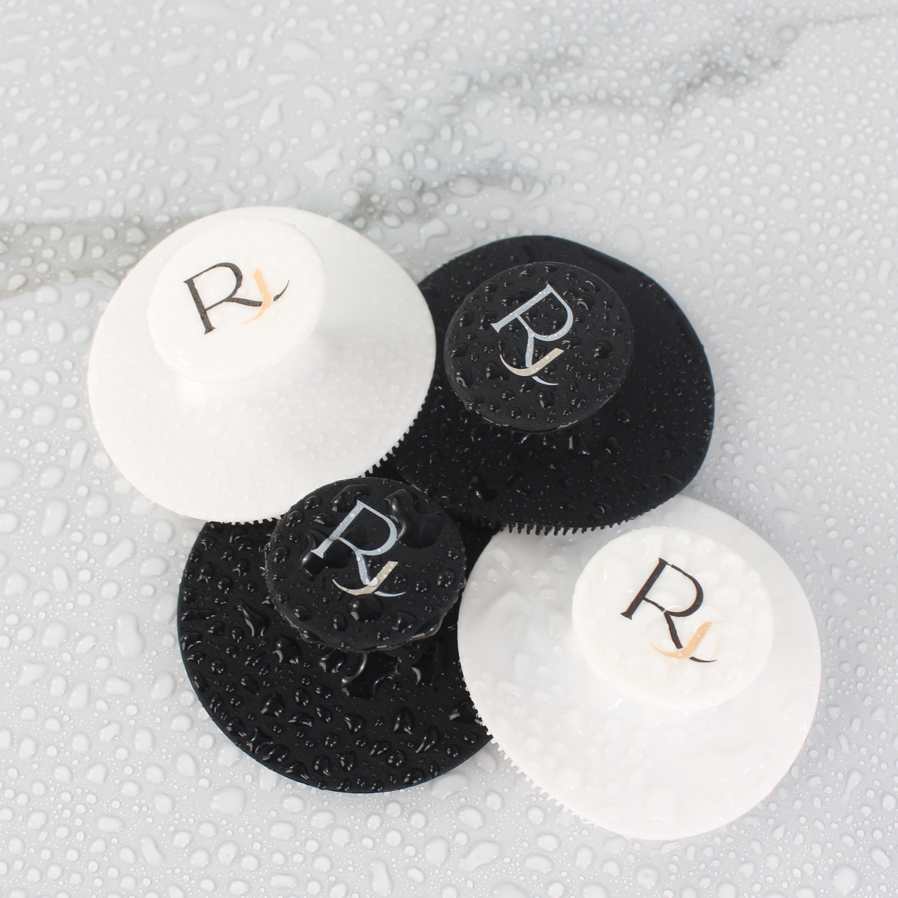 Black and White Raqiia Face Cleansers on wet white marble