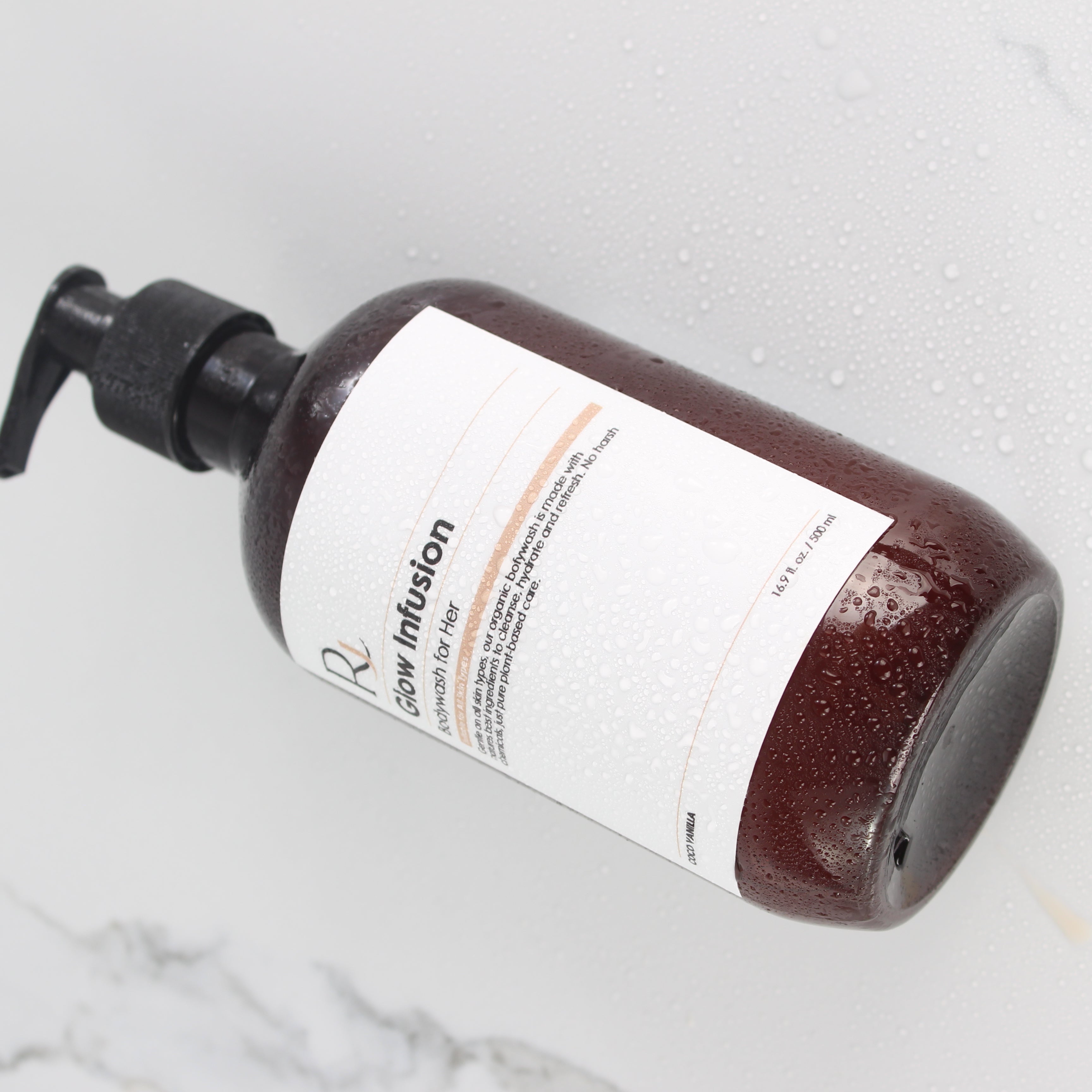 Bottle of Raqiia Glow Infusion Bodywash with pump on a white marble surface