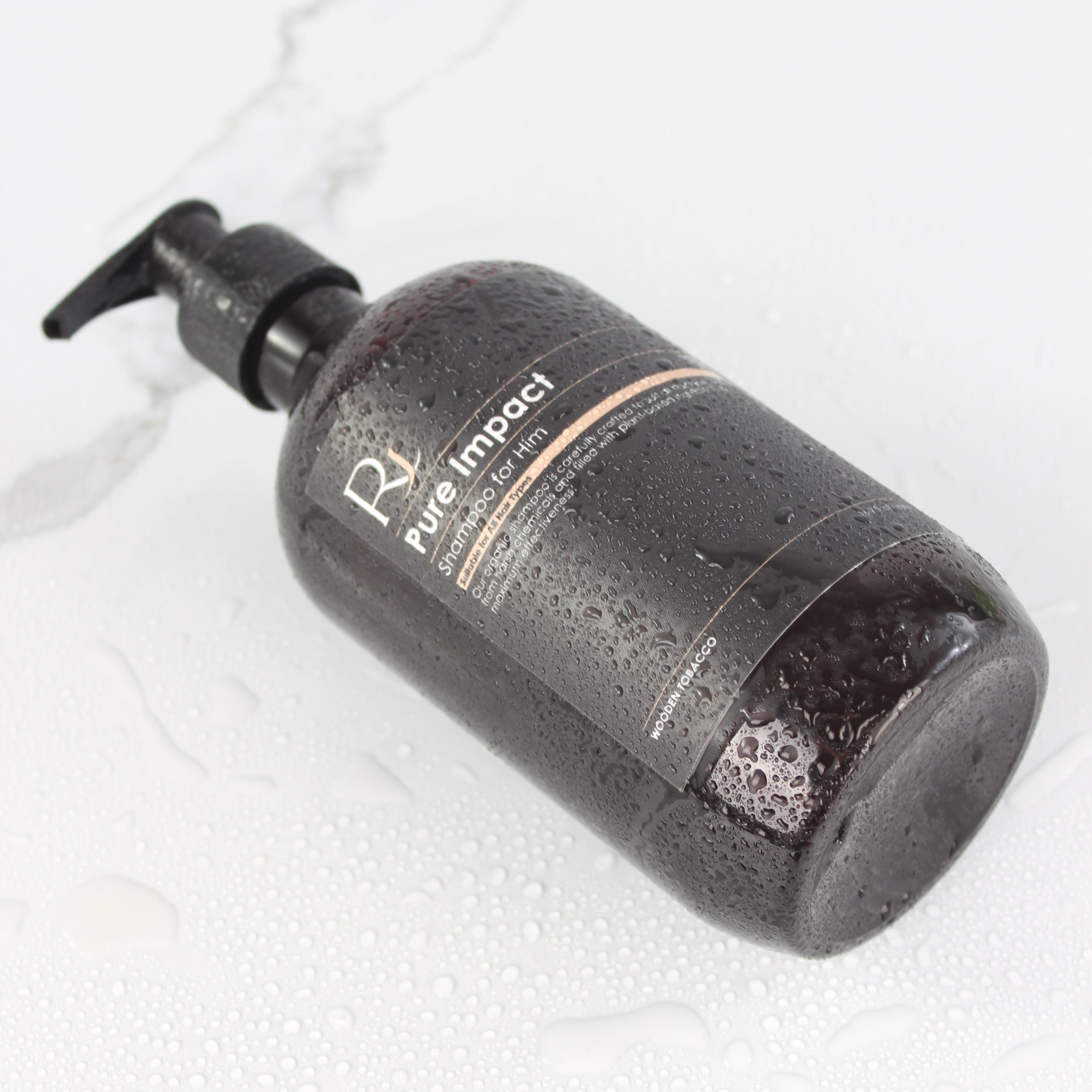 Amber bottle of Raqiia Pure Impact Shampoo on a white marble