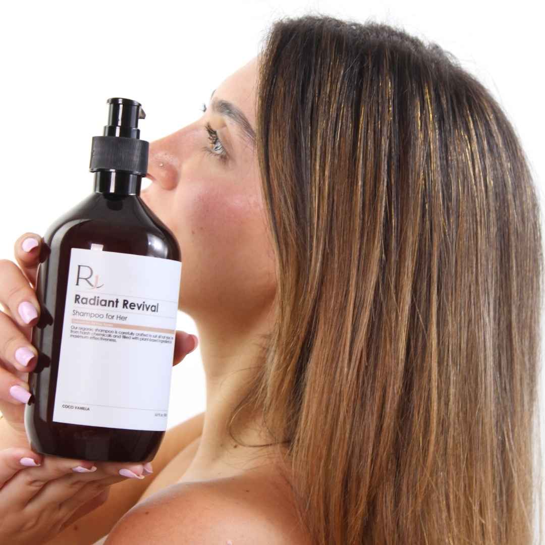 Woman holding a bottle of 'Raqiia Radiant Revival' shampoo with long, styled hair.