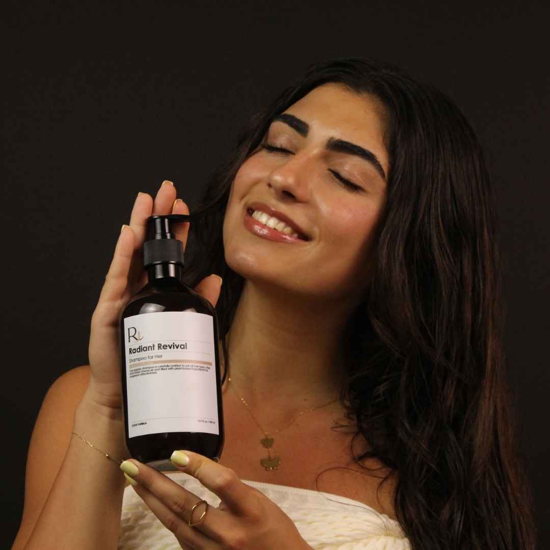 Woman holding a bottle of Raqiia 'Radiant Revival' against a dark background