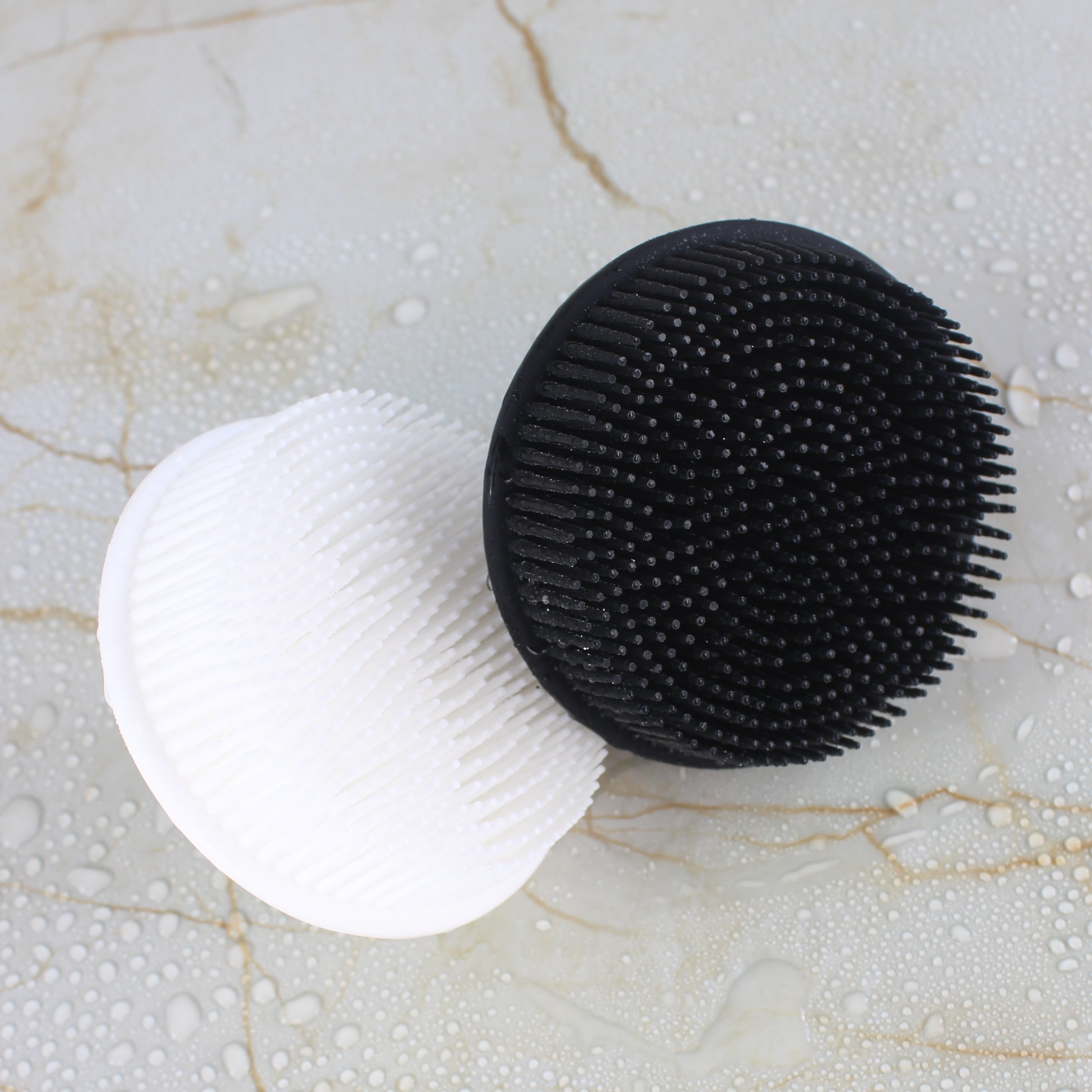 Black and white Raqiia Body scrubber on a marble surface with water droplets