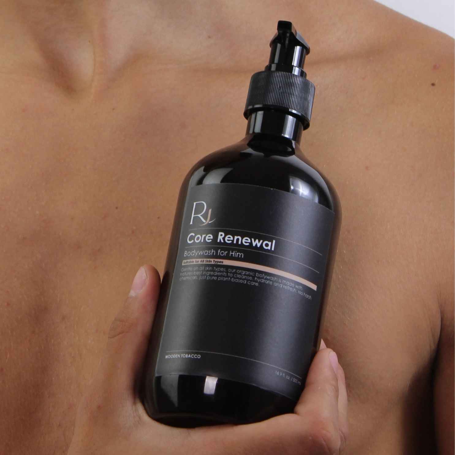 Model holding Raqiia Core Renewal Bodywash close to shoulder