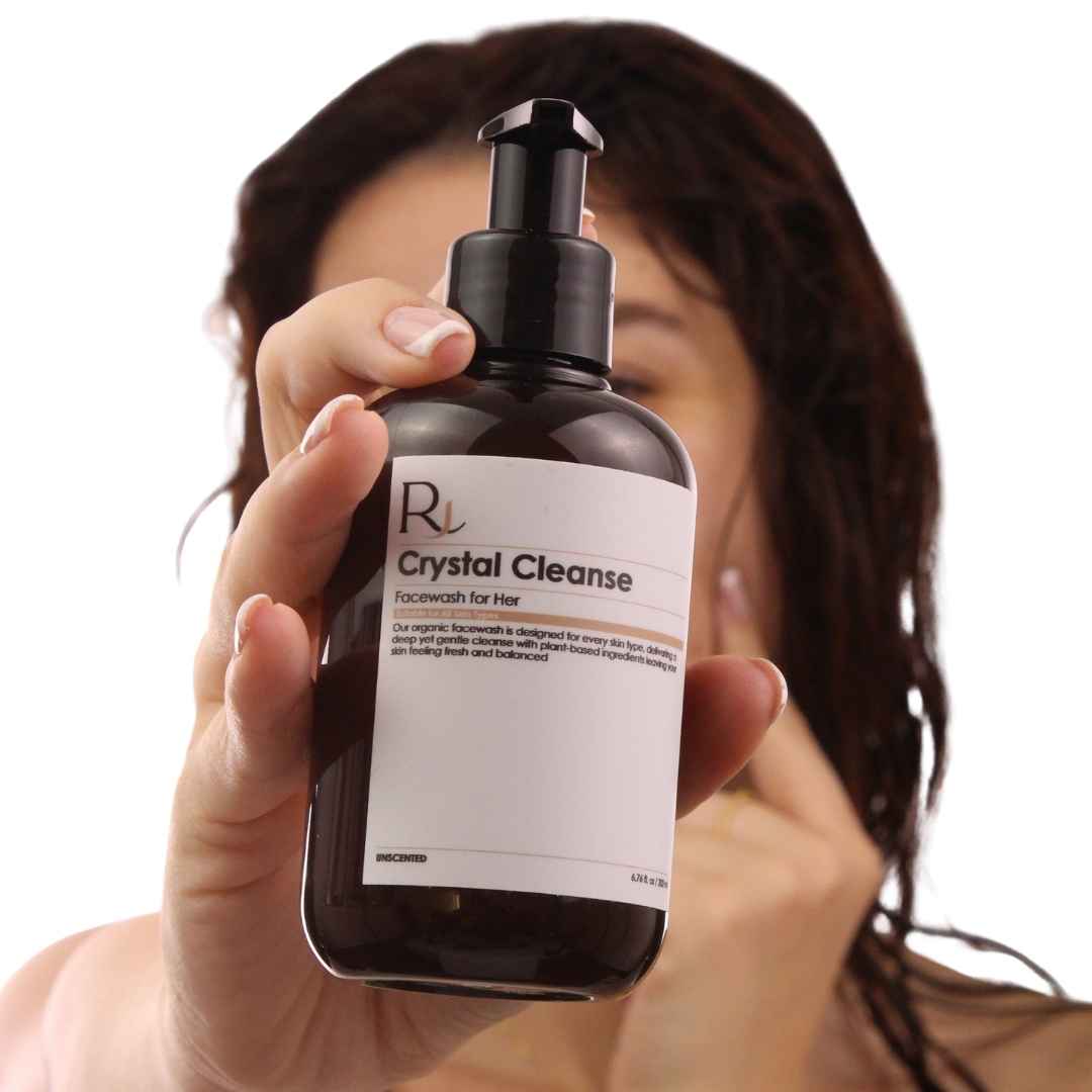 Person holding a bottle of 'Raqiia Crystal Cleanse' facial wash with a blurred background
